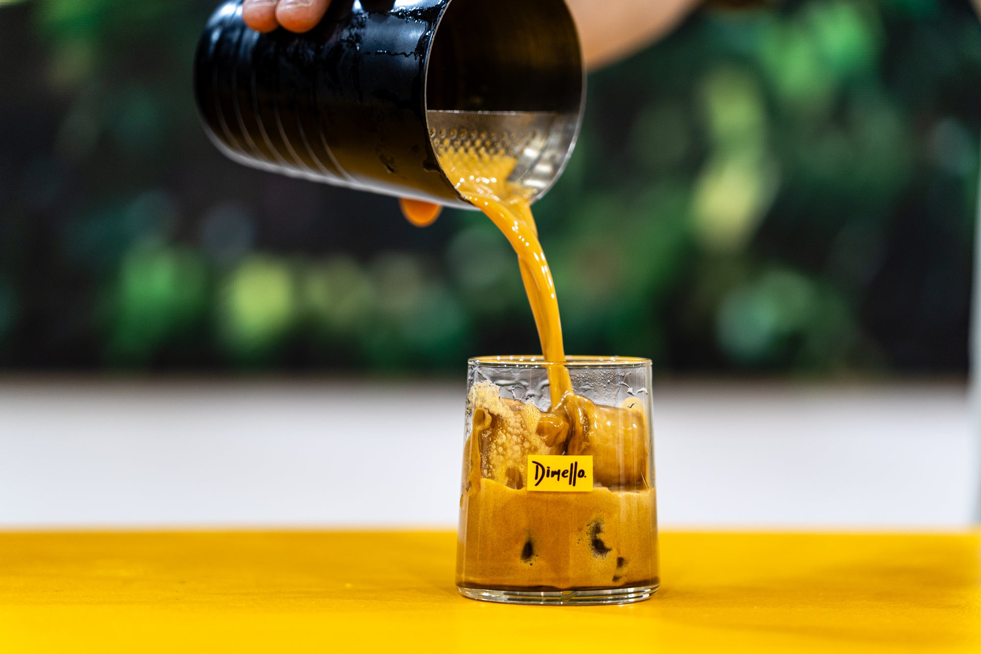 Pouring a drink into a glass with a blurred green background